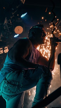 a man crouching on a stage with sparklers in his hair