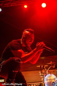 a man crouching on stage in front of a red light