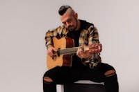 a man playing an acoustic guitar in front of a white background